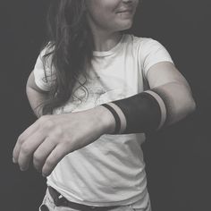 a woman wearing a white shirt and black wristbands is holding her arm in the air