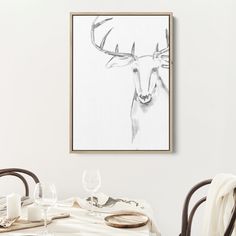 a framed deer head on the wall above a dining room table with place settings and utensils