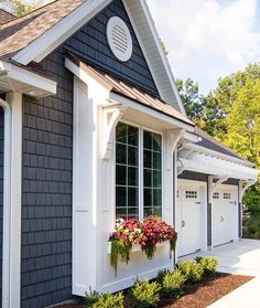 a black and white house with flowers in the window boxes on the front porch area