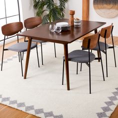 a dining room table with chairs and a rug on the floor in front of it