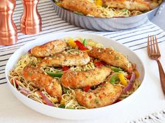 two white bowls filled with chicken and noodles on top of a striped table cloth next to copper utensils