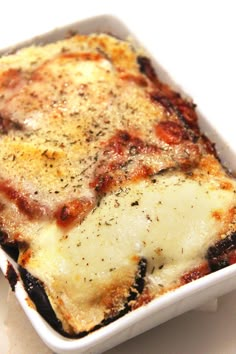 a casserole dish with cheese and meat in it on a white tablecloth