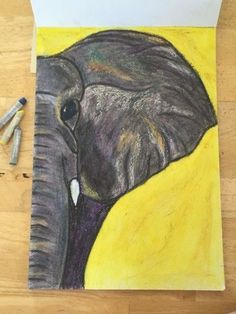 a drawing of an elephant on a piece of paper with crayons next to it