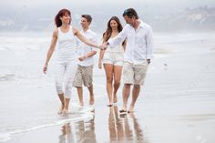 four people walking on the beach holding hands