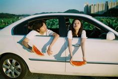 two people sitting in the back of a car with watermelon slices on them