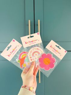 a person holding up some stickers in front of a blue door with pink flowers on it