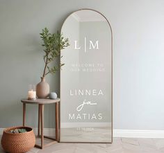 a large mirror sitting on top of a table next to a vase and potted plant