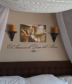 a couple kissing each other in front of two pictures on the wall above a bed