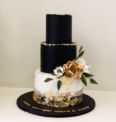 a three tiered black and gold wedding cake