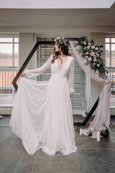 a woman in a white dress standing next to a window