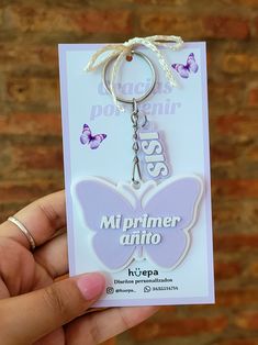 a keychain with a butterfly on it is being held in front of a brick wall