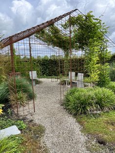 an outdoor garden with chairs and trelliss on the ground, surrounded by greenery