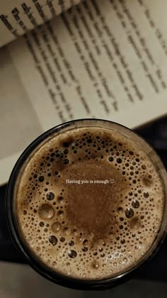 a cup of coffee sitting on top of a table next to an open book