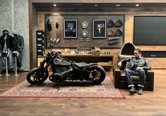 a man sitting on a chair next to a motorcycle in a room filled with mannequins