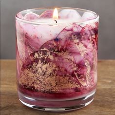 a candle that is sitting in a glass vase on top of a wooden table,