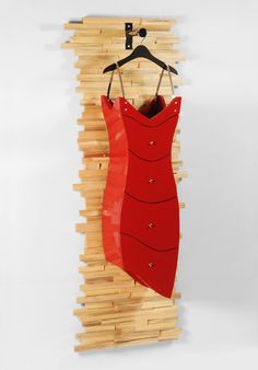 a red dress hanging on a wooden wall