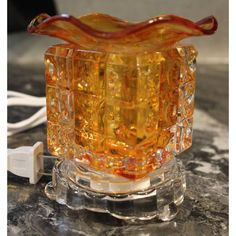 an orange glass object sitting on top of a table next to a charger plugged in