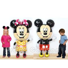 three children standing next to each other in front of mickey and minnie mouse balloon sculptures