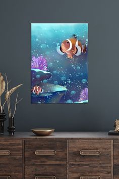 an underwater scene with clown fish and seaweed in the foreground, framed on a wall