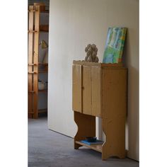 a wooden cabinet sitting next to a wall with a teddy bear on top of it