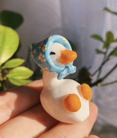 a small toy duck sitting on top of a person's hand