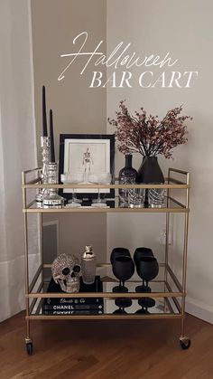 a gold bar cart with black and white items on it, sitting in front of a wall