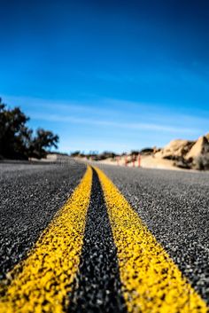 an empty road with yellow lines on the side and blue sky in the background royalty images