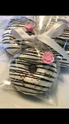 three decorated donuts wrapped in cellophane with pink roses