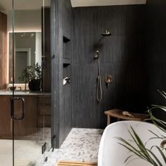 a bathroom with a tub, sink and shower head in it's black wood paneling