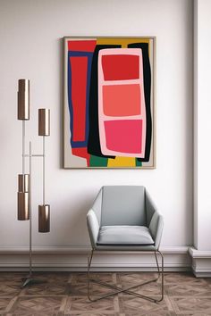 an abstract painting hangs on the wall next to a chair and floor lamp in a white room