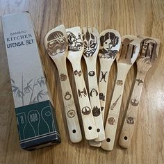 five wooden spoons with designs on them sitting next to a package of kitchen utensils