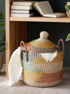 a large woven basket sitting on top of a wooden table next to a book shelf