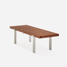 a wooden bench sitting on top of a white floor next to a metal frame structure