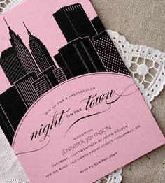 a pink and black night on the town wedding card with cityscape in the background