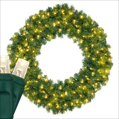 a christmas wreath with lights on it next to a pair of green rubber boots and a white background