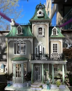 a doll house with green roof and balcony