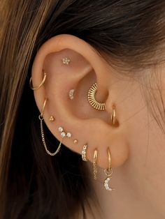 a woman's ear with several different types of piercings