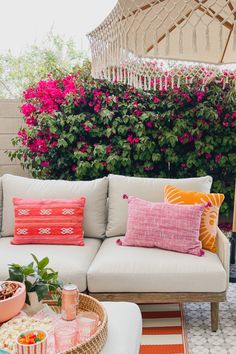 a white couch sitting on top of a wooden table next to a pink flower bush