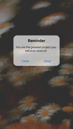 an iphone screen with the message reminderr on it and flowers in the foreground