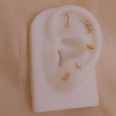 a pair of ear rings sitting on top of a white stand next to a sheet