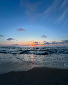 the sun is setting over the ocean with waves coming in to shore and blue sky