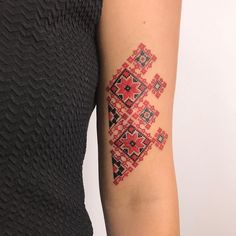 a woman's arm with a red and black cross - stitch tattoo on it