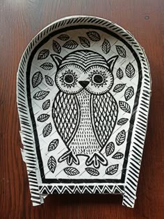 a paper plate with an owl design on the front and sides, sitting on a wooden surface