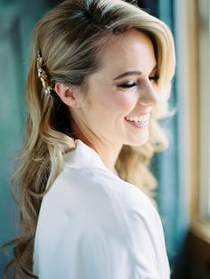 a woman with long hair wearing a white shirt and gold headpiece smiling at the camera