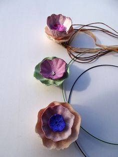 three different colored flowers on a white surface