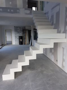 an empty room with white stairs leading up to the second floor