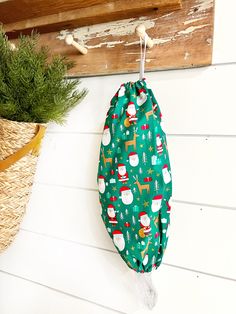 a green bag hanging on the side of a wall next to a potted plant