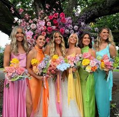 a group of women standing next to each other in dresses and holding bouquets with flowers on them