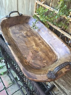 a large wooden tray sitting on top of a metal rack next to a fence and tree