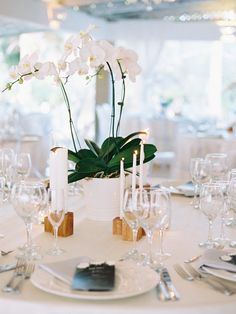 a table set for dinner with white flowers and candles